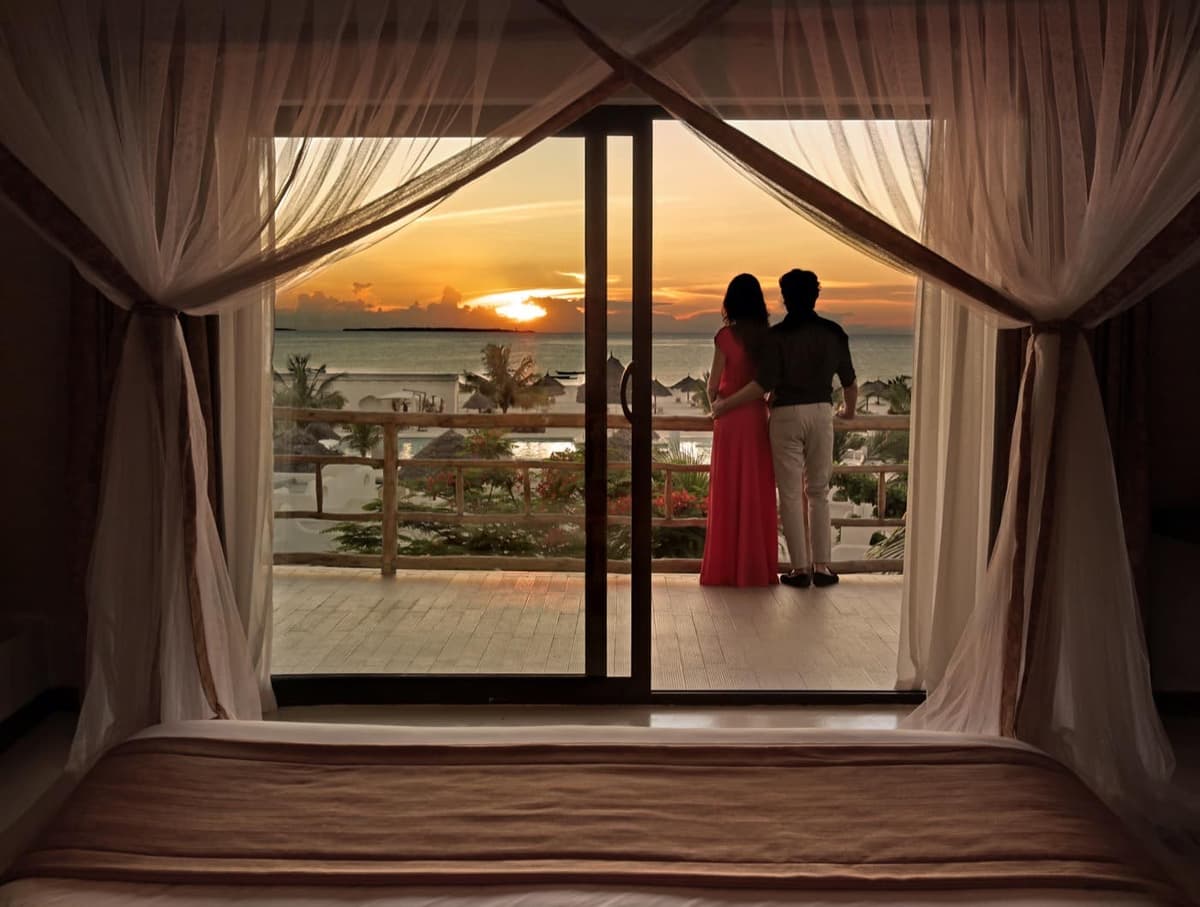 Couple watching the sunset over the Indian Ocean from a private villa balcony at Nungwi, Zanzibar
